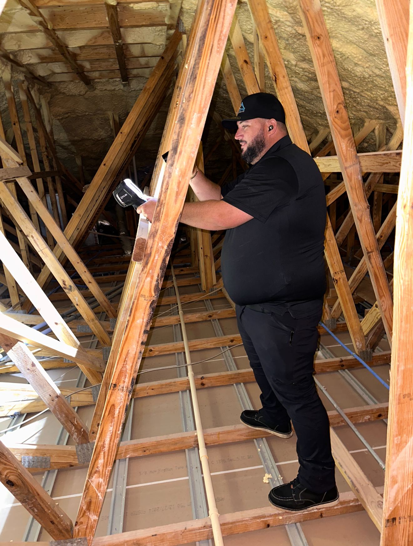 Inspector examining roof framing for moisture